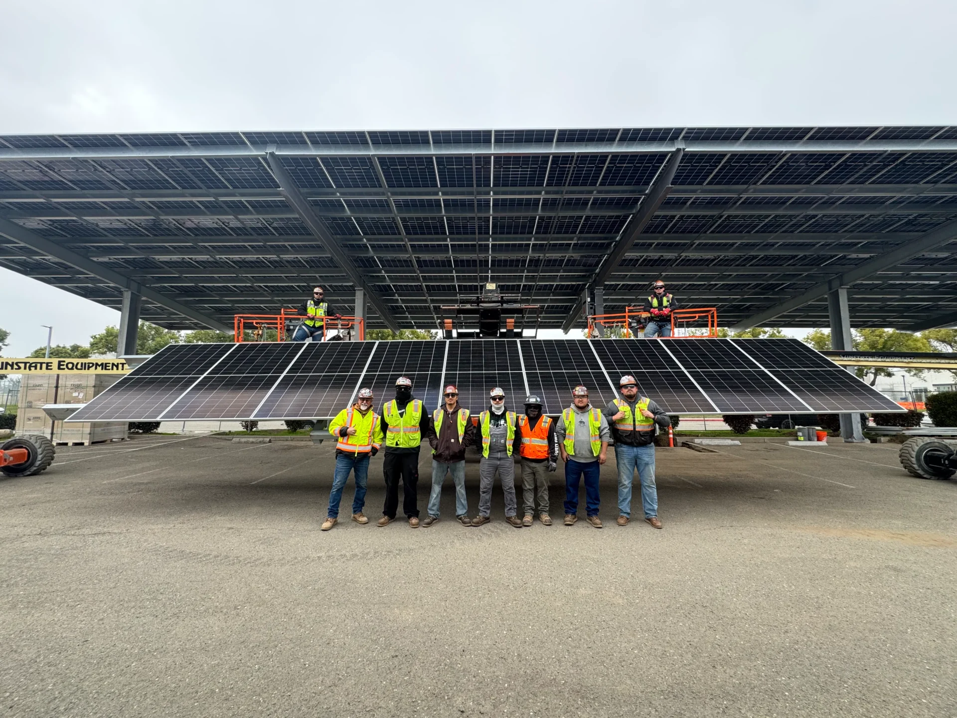 Construction workers stand in front of a large stadium seating area under a roof.